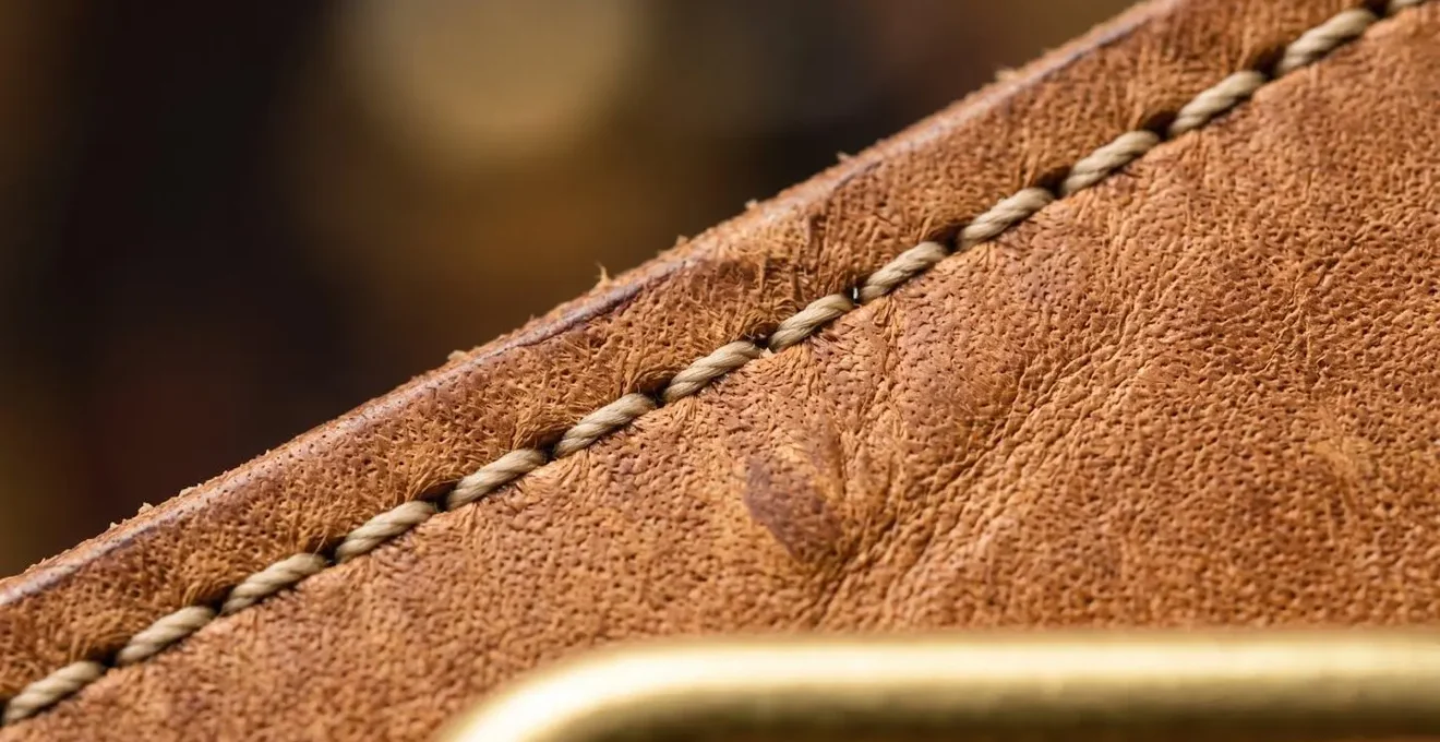 Extreme close-up of genuine leather grain texture and precise stitching on luxury handbag
